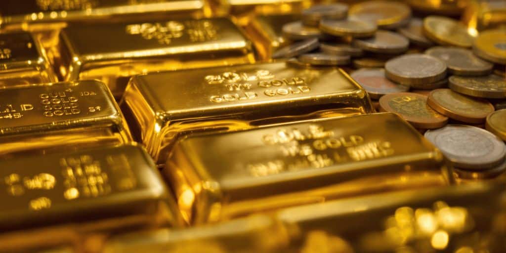 Lingots d'or empilés à côté de pièces de monnaie.