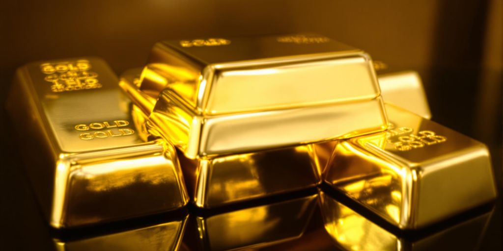 Lingots d'or brillants empilés sur une surface sombre.