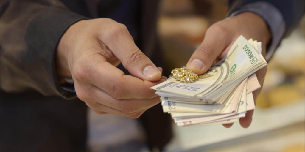 Billets froissés et pièces de monnaie éparpillées sur une table en bois.
