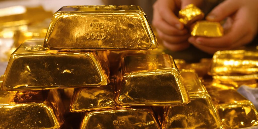 Lingots d'or brillants sur fond sombre, mains tenant de l'or