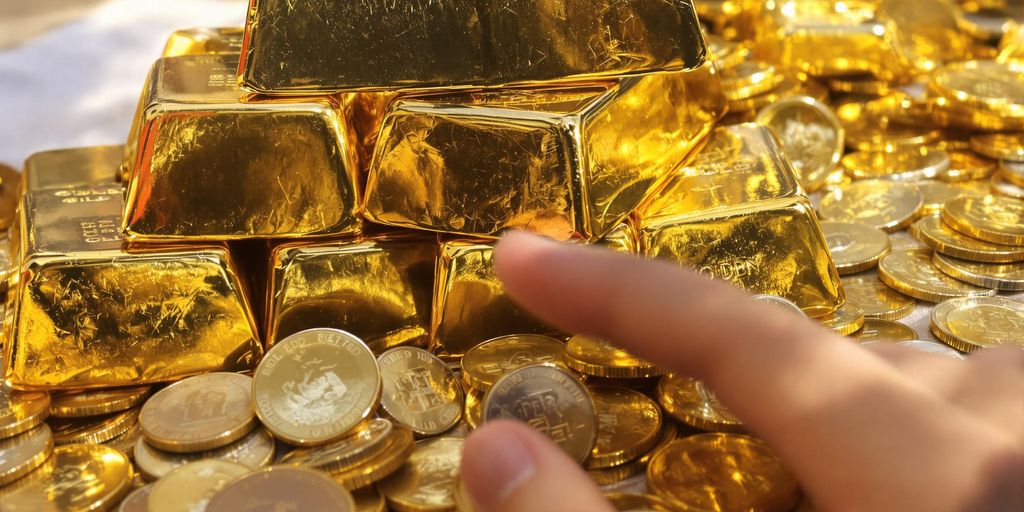 Lingots d'or et pièces d'or dans une main.