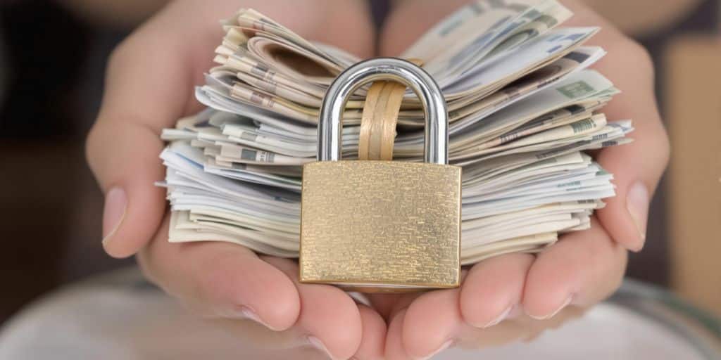 Pièces, billets, cadenas, mains protégeant argent.