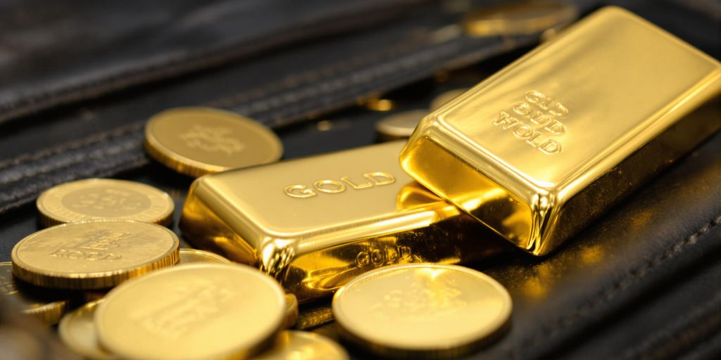 Lingots d'or et pièces dans un portefeuille ouvert.