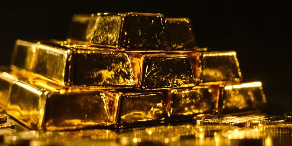 Lingots d'or et pièces sur un fond sombre.