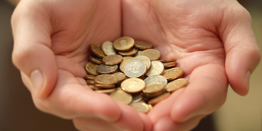 Mains protégeant des pièces de monnaie