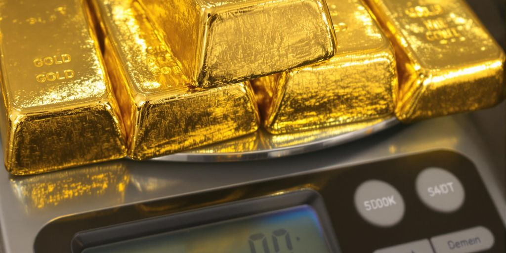 Lingots d'or empilés sur une balance numérique.