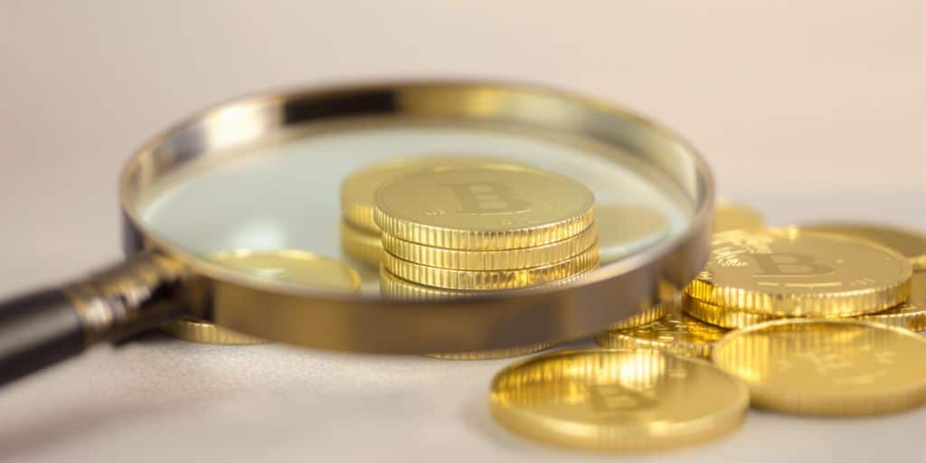 Pièces d'or empilées avec une loupe