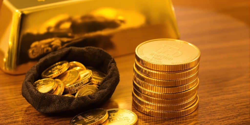 Pièces d'or brillantes empilées, bourses, lingots sur table.