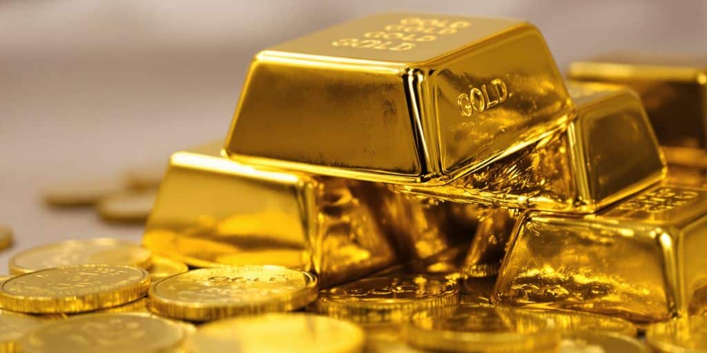 Lingots d'or empilés et pièces d'or brillantes.