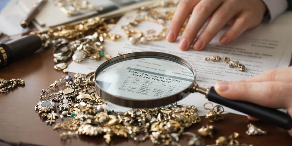Mains, loupe, bijoux et documents.
