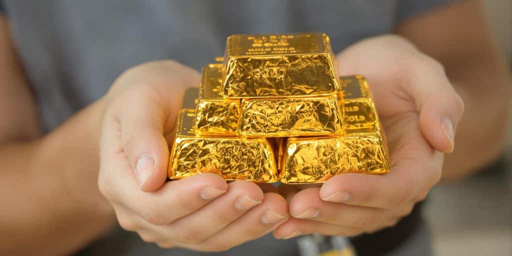 Lingots d'or empilés, mains les tenant