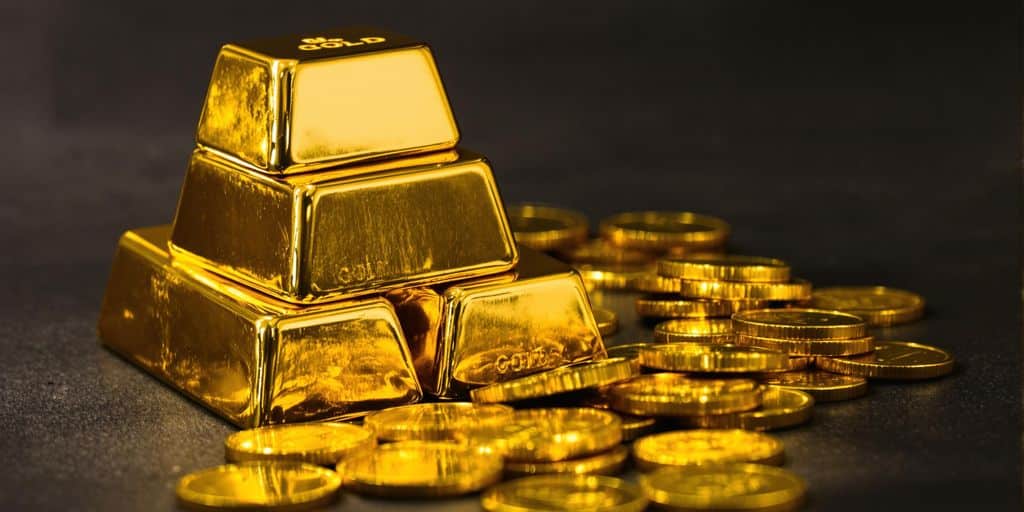 Lingots et pièces d'or brillants sur fond noir.