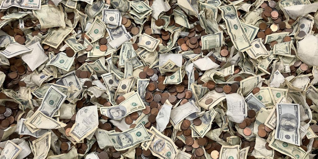 Billets froissés et pièces de monnaie mélangés dans une machine de recyclage.