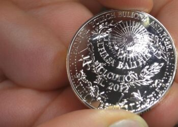 Une main tenant une pièce d'argent brillante.