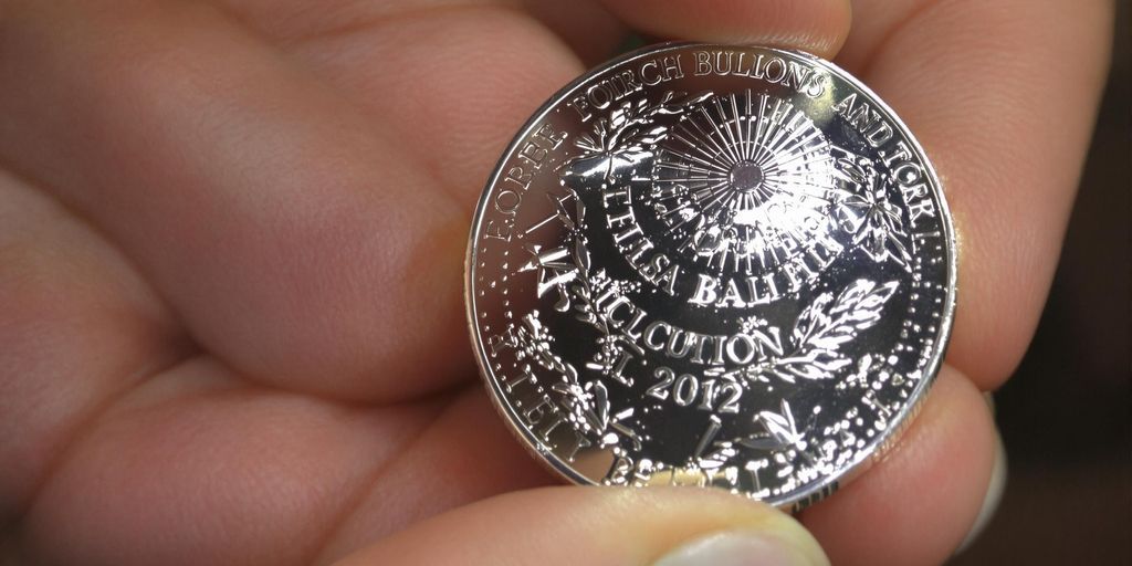 Une main tenant une pièce d'argent brillante.