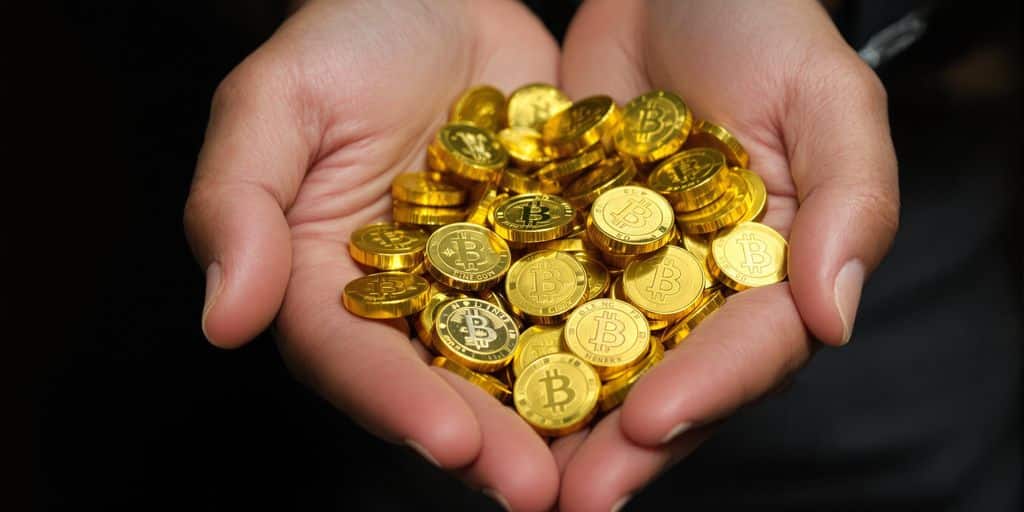 Une main tenant des pièces de monnaie dorées.