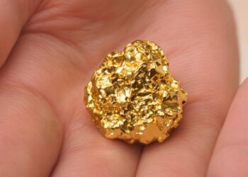 Main tenant une pépite d'or brillante