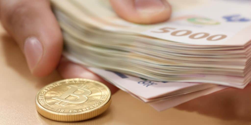 Une main tenant de l'argent liquide et une pièce d'or.