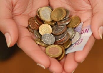 Main tenant des pièces de monnaie et des billets.