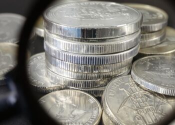 Pièces en argent empilées et une loupe.