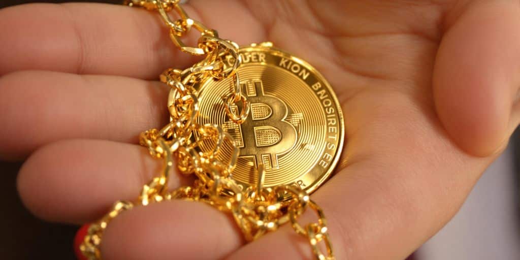 Une main tenant une pièce d'or avec une chaîne d'assurance.