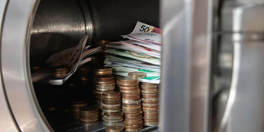Pile de pièces et billets de banque dans un coffre.