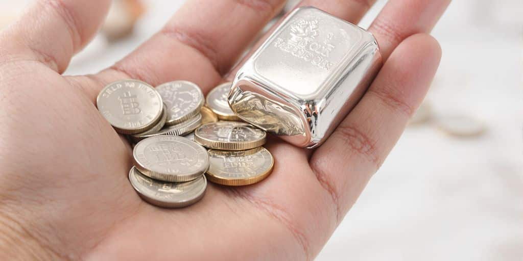 Argent, pièces et lingots dans une main.