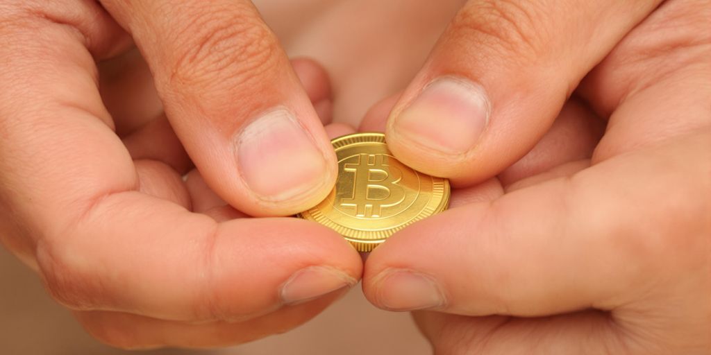 Main âgée et main jeune manipulant une pièce d'or.
