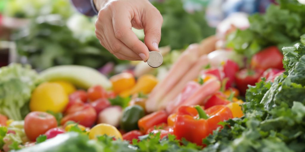 Main tendant une pièce de monnaie à des fruits frais.