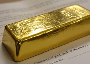 Lingot d'or posé sur un contrat de succession.