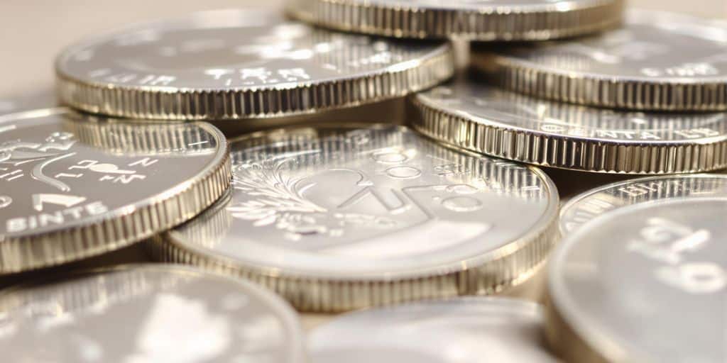Pièces d'argent brillantes, diversifiées, empilées sur fond clair.