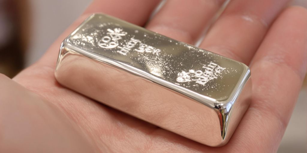 Lingot d'argent brillant posé sur une paume.