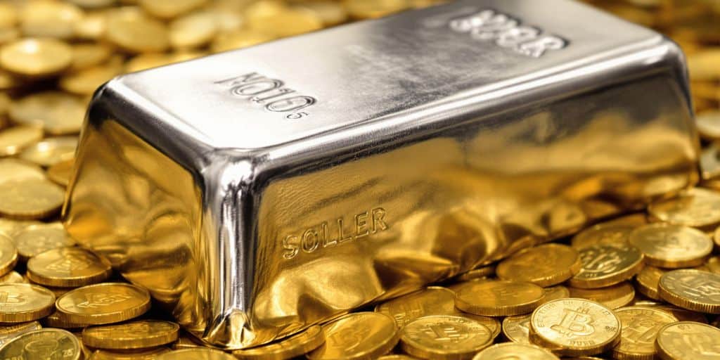 Lingot d'argent brillant posé sur un tas de pièces d'or.