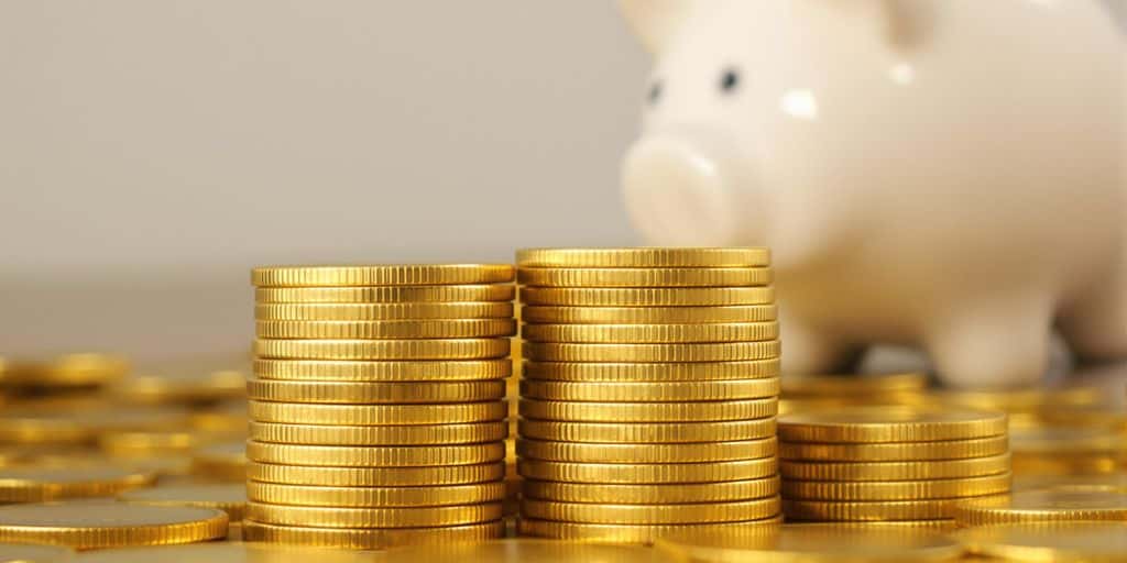 Pièces d'or empilées devant une tirelire cochon.