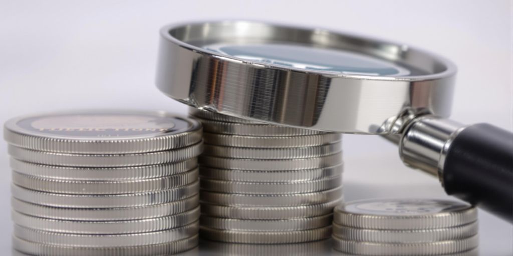 Pièces d'argent empilées avec une loupe.