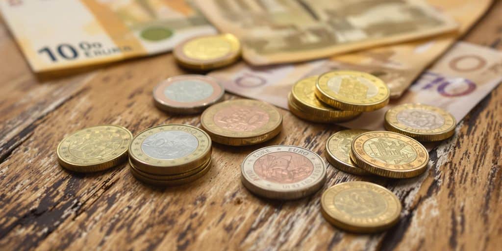 Pièces de monnaie et billets sur une table en bois.