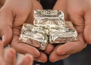 Des mains passant des lingots d'argent à des enfants.