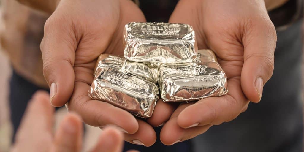 Des mains passant des lingots d'argent à des enfants.
