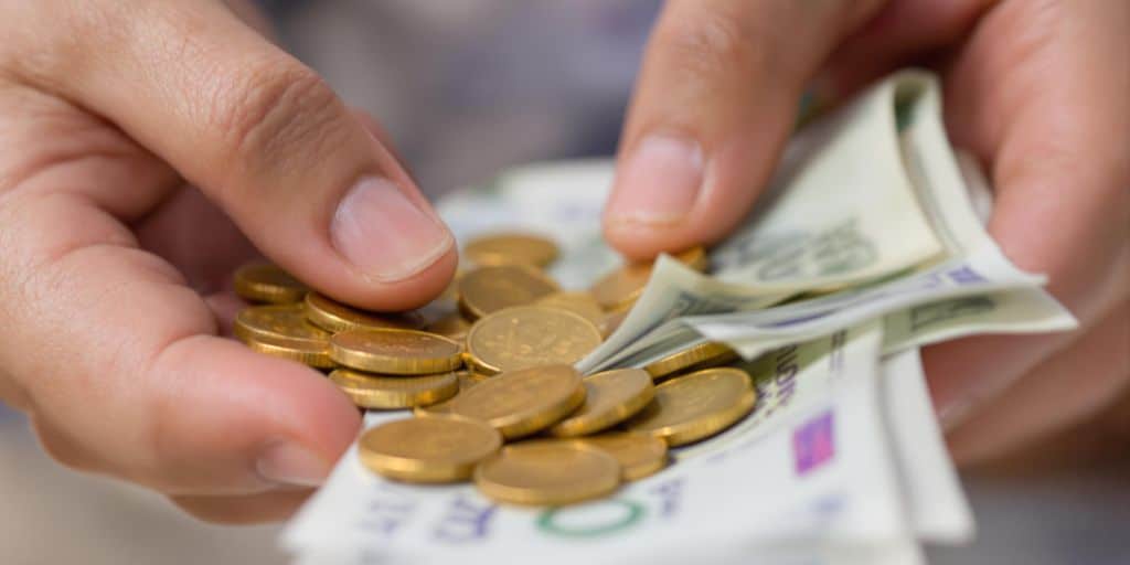 Mains échangeant des pièces d'or et des billets.