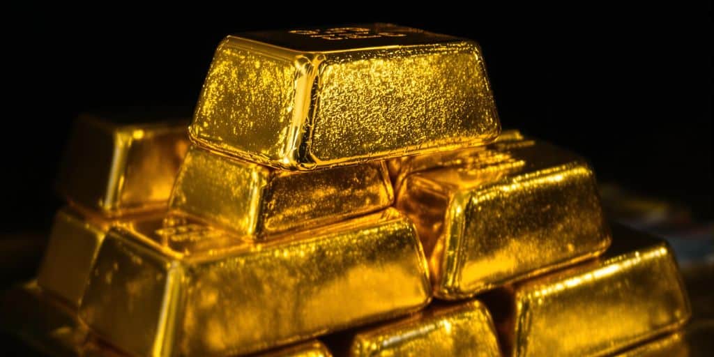 Lingots d'or brillants empilés sur un fond sombre.