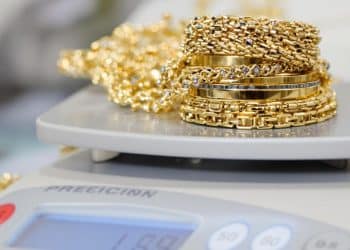 Bijoux en or empilés sur une balance de joaillier.