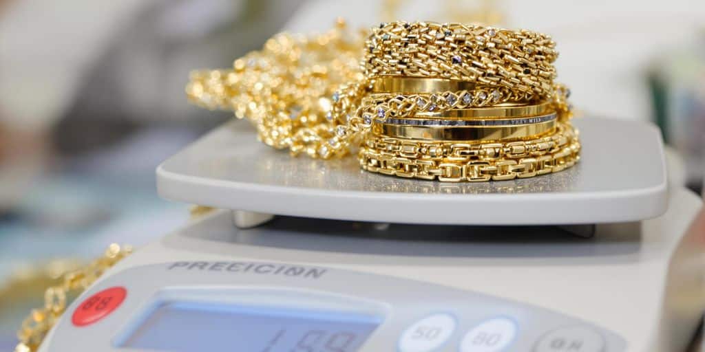 Bijoux en or empilés sur une balance de joaillier.