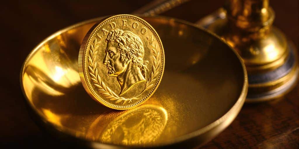 Pièce en or Napoléon posée sur balance ancienne en laiton.