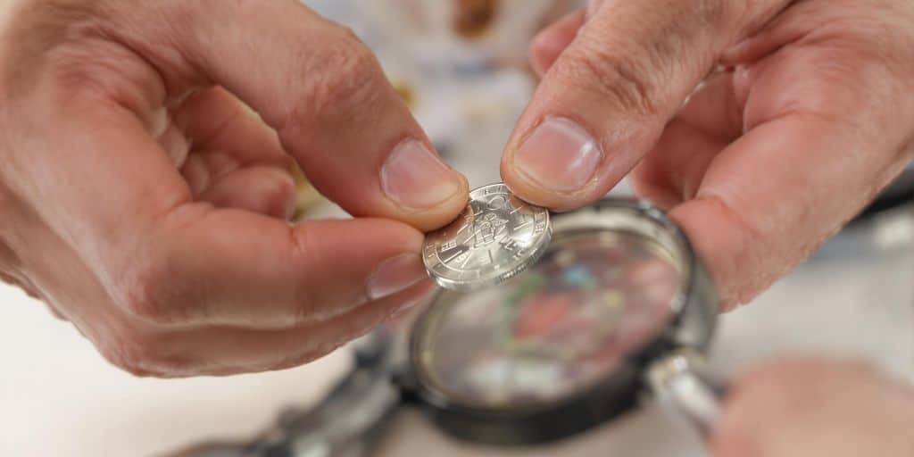 Main examine fausse pièce d'argent, loupe