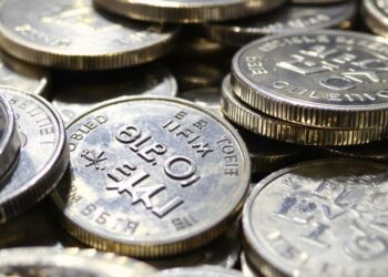 Pièces d'argent brillantes empilées, certaines avec des marques douanières.