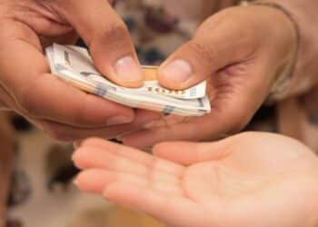 Main adulte donne de l'argent à un enfant.