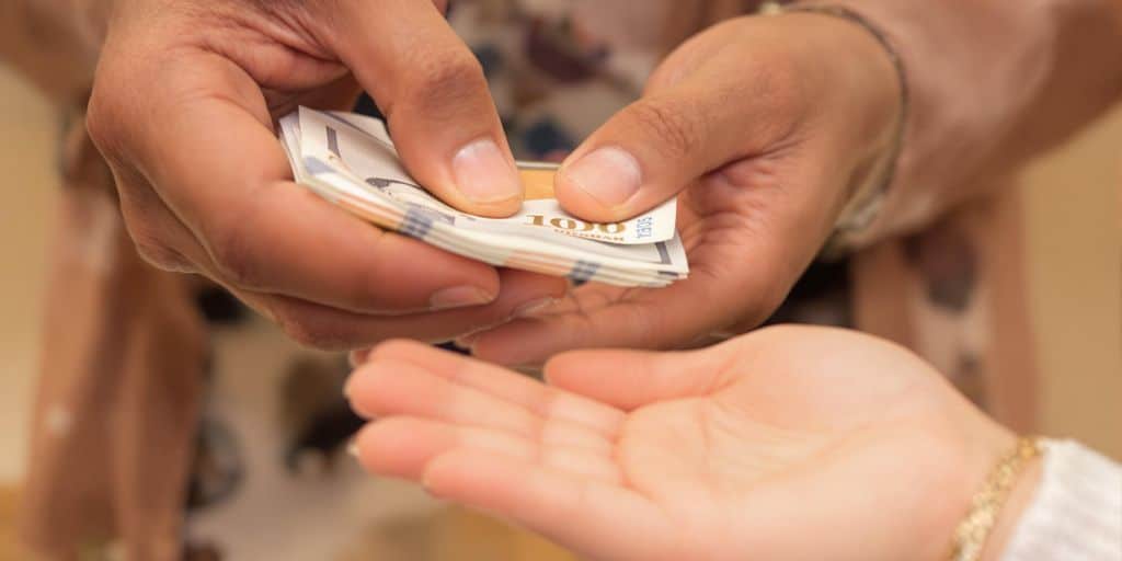 Main adulte donne de l'argent à un enfant.