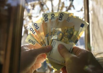 Mains passant des billets de banque à travers une fenêtre.