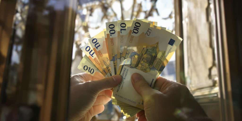 Mains passant des billets de banque à travers une fenêtre.