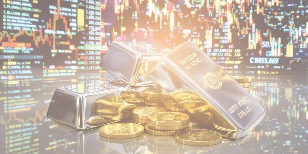 Lingots d'argent et pièces d'or à côté d'un écran d'ordinateur affichant des cryptomonnaies.